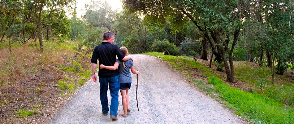 Andrew Tanis walking down a road less traveled with his daughter in Amador Wine Country near Tanis Winery.